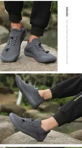 Dettaglio scarpe da camminata in maglia grigia indossate all'aperto su terreno roccioso