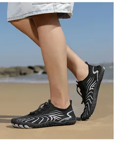 Nahaufnahme von schwarzen, atmungsaktiven Wasserschuhen mit weißen Mustern am Sonnenstrand.
