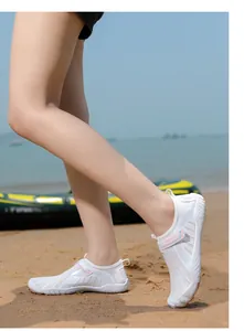 Side view of breathable white wading shoes worn by a model on a sunny sandy beach.