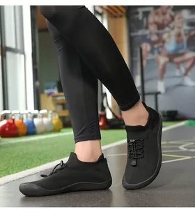 Dettaglio ravvicinato di scarpe a calzino nere in flyknit con coulisse indossate in una palestra