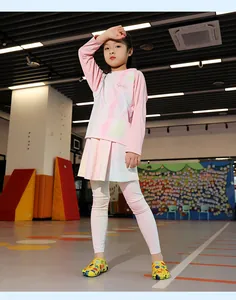 Kid modeling quick-dry water shoes and pink sports outfit in an indoor gym hall.