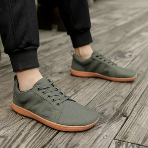 Detailed view of olive green wide toe box barefoot sneakers for men on a wooden deck