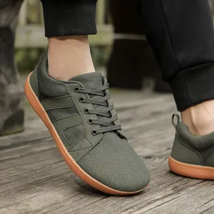 Detailed view of olive green mesh barefoot shoes with a wide toe box on a wooden floor.