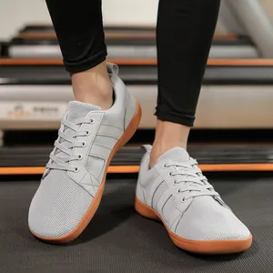 Detail of gray wide-toe barefoot training shoes with gum soles on a treadmill gym floor