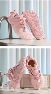 Close-up of pink children's five-finger sports shoes on a white table and speaker.