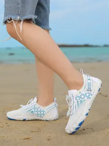 Children's white and blue anti-slip water shoes for beach activities shown on sand