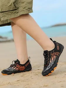 Breathable black and orange children's water shoes on sandy beach background