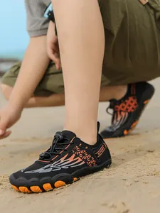 Close-up of children's non-slip water shoes with vibrant orange flame pattern on beach