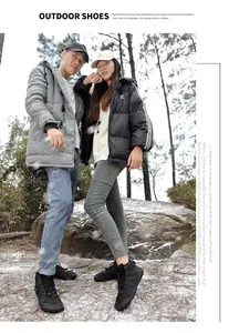 Couple wearing black minimalist barefoot snow boots in a snowy outdoor forest setting