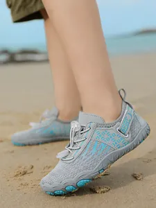 Close-up view of grey and blue children's water shoes worn on a sandy beach