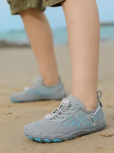 Grey children's wading shoes shown on a sandy beach with breathable mesh and laces