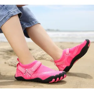 Primo piano di scarpe da acqua rosa per bambini con velcro su una spiaggia sabbiosa