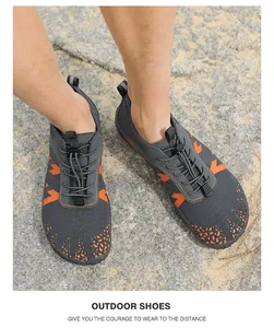 Primo piano di scarpe da scoglio grigie e arancioni su un terreno sabbioso all'aperto.