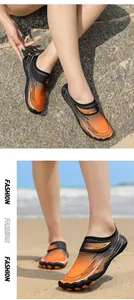 Primo piano di scarpe da scoglio arancioni e nere per escursioni e nuoto in spiaggia