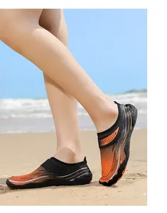 Scarpe acquatiche sfumate arancione e nero indossate sulla spiaggia per attività all'aperto