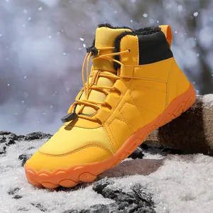 Detailed view of yellow waterproof snow boots with black fur lining on snowy ground.