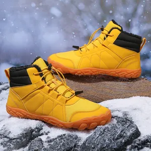 Close-up of yellow barefoot-style snow boots with warm fur lining on snowy ground
