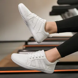 Close-up of white wide-toe barefoot training shoes in a dynamic fitness gym setting