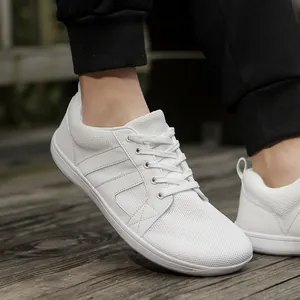 Detail view of white wide-toe barefoot training shoes for men on a wooden surface
