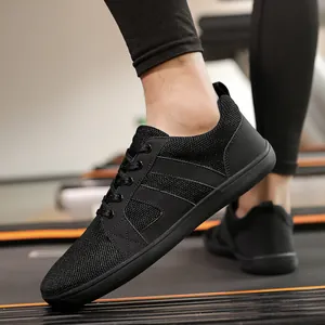 Close-up of black wide toe box barefoot training shoes being worn on a gym treadmill.