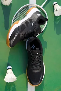 Gros plan de chaussures de badminton noires professionnelles sur terrain avec raquette