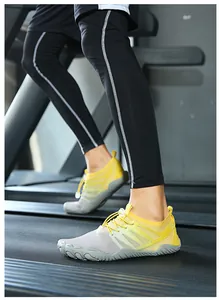 Macro detail of yellow and gray five-finger barefoot shoes worn on a gym treadmill