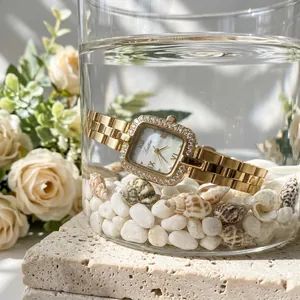 Primo piano dell'orologio Scottie d'oro in acqua con conchiglie e rose bianche di sfondo