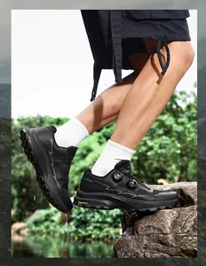 Black waterproof outdoor cycling and hiking shoes with rotary lacing system on rock