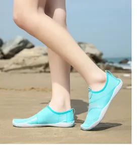 Dettaglio di scarpe da scoglio azzurre traspiranti indossate su una spiaggia sabbiosa