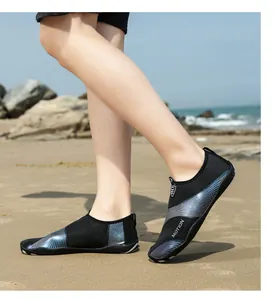 Dettaglio di scarpe da scoglio nere traspiranti indossate da una persona su una spiaggia