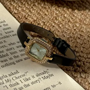 Luxuriöse quadratische Scottie Quarzuhr mit Strass-Lünette auf einer Buchseite