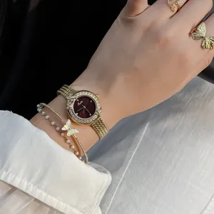 Close-up view of elegant Scottie gold quartz watch with diamond-set wreath on woman's wrist