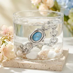 Detail of silver chain quartz watch with blue dial submerged in a glass of water
