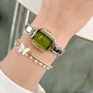 Close-up of elegant Scottie women's watch with emerald green dial and jewelry bracelets