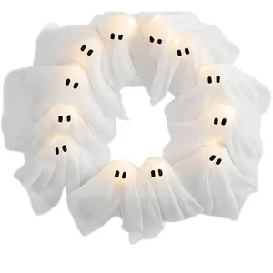 Close-up of circular Halloween ghost wreath candle arrangement with warm glowing light