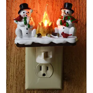 Detailed view of Christmas snowman and campfire night light plugged into a wall socket