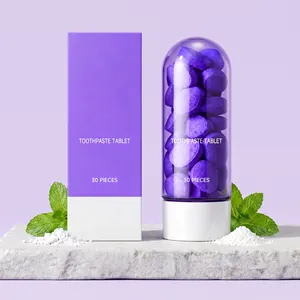 Gros plan de comprimés de dentifrice violets dans un flacon capsule et menthe