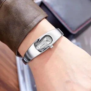 Nahaufnahme einer silbernen Y2K-Bangle-Uhr in Tropfenform mit feinen Metalldetails am Handgelenk