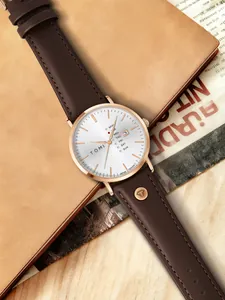 Detaillierte Makroansicht der TOMI Quarzuhr mit braunem Lederarmband und Datumsanzeige.