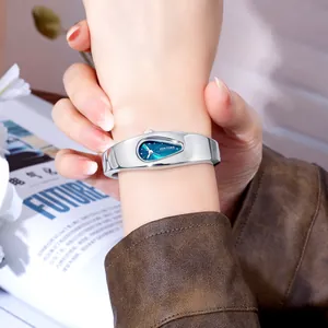 Nahaufnahme einer silbernen Y2K-Armreif-Uhr mit blauem Zifferblatt am Handgelenk