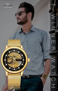 Close-up of a gold-tone skeleton mechanical watch with a mesh strap on a male model.