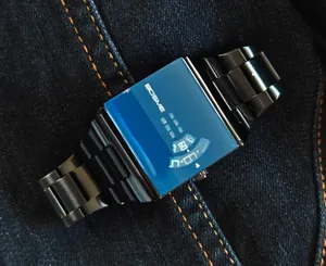Gros plan d'une montre homme carrée moderne avec verre teinté bleu et bracelet en acier noir