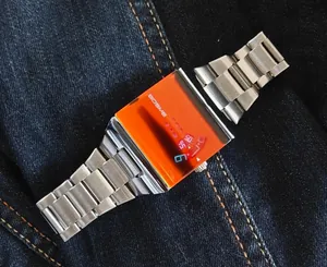 Vue détaillée d'une montre à quartz carrée pour homme avec cadran orange et bracelet acier