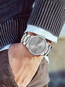 Detailed view of silver TOMI quartz watch on wrist featuring grey sunray dial and rhinestones