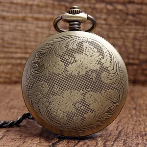 Vintage bronze pocket watch with intricate floral engraving on rustic wood background.