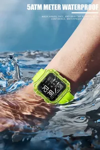 Détail de la montre numérique carrée SMAEL vert citron immergée dans l'eau bleue.