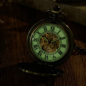 Close-up of luminous Roman numeral dial on vintage bronze mechanical skeleton pocket watch