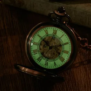 Detail showing the green luminous dial and skeleton movement of a retro pocket watch