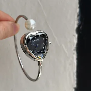 Close-up of SUNLIFEX heart-shaped bangle watch featuring pearl and diamond accents.