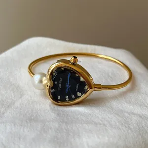 Detailed macro view of gold heart-shaped bangle watch with pearl and SUNLIFEX dial